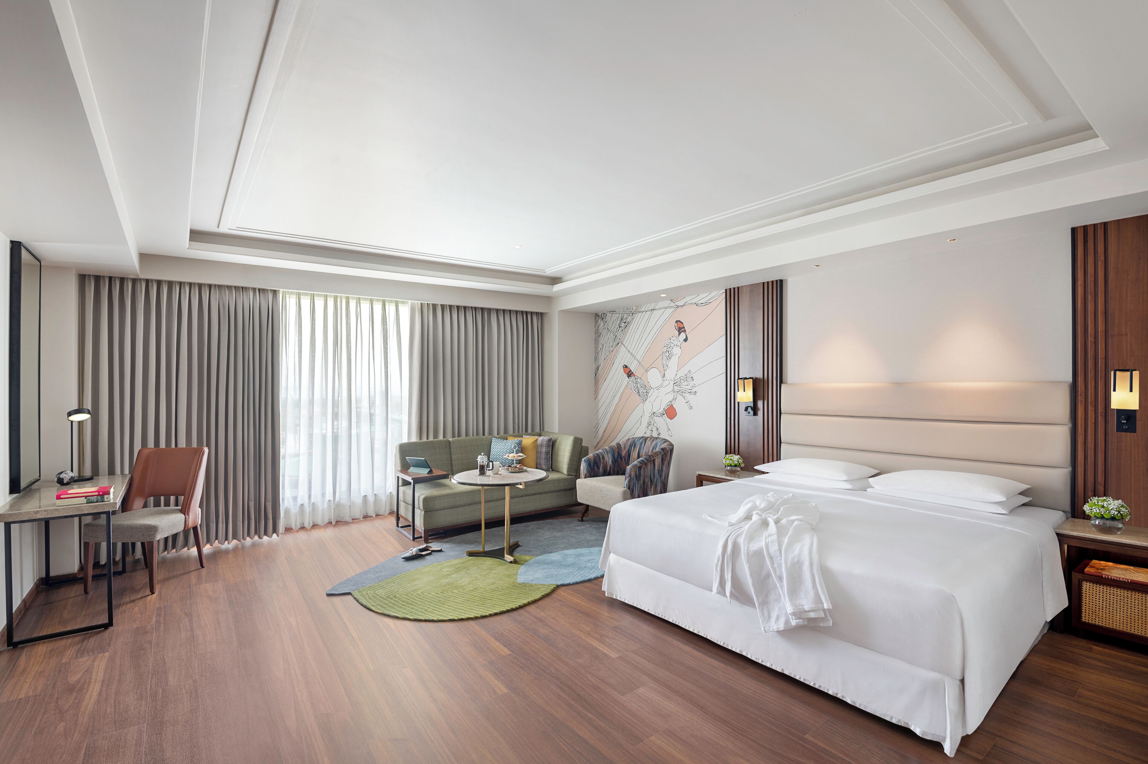 Een moderne hotelkamer met een groot bed, een bureau, een bank en een kleine tafel.