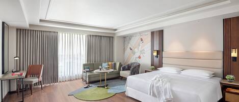 Una habitación de hotel moderna con una cama grande, un escritorio, un sofá y una mesita.