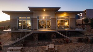 A modern house with a stone patio, outdoor seating, and a staircase leading to the entrance. -  Casa Buena Vista (Valle de Guadalupe)