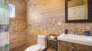 A bathroom with a shower, toilet, and sink area. - Casa Buena Vista (Valle de Guadalupe)