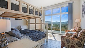 A room with a bunk bed, a desk, a chair, and a view of the countryside through large windows. -  Casa Buena Vista (Valle de Guadalupe)