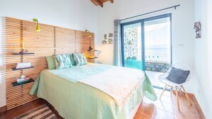 Un dormitorio con cama, una silla, un ventanal y vistas al exterior.
