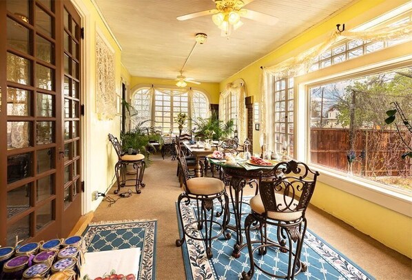 Enjoy meals in this elegant dining area with a long table and comfortable chairs, surrounded by large windows and decorative elements.