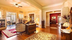 A spacious living room with hardwood floors, a large rug, a fireplace, and a bookshelf. - Queen Size Suite with a shared Hallway Bath (Gainesville)