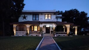 A two-story house with a central entrance, a star on the facade, and a paved driveway leading to the front door. - Queen Size Suite with a shared Hallway Bath (Gainesville)