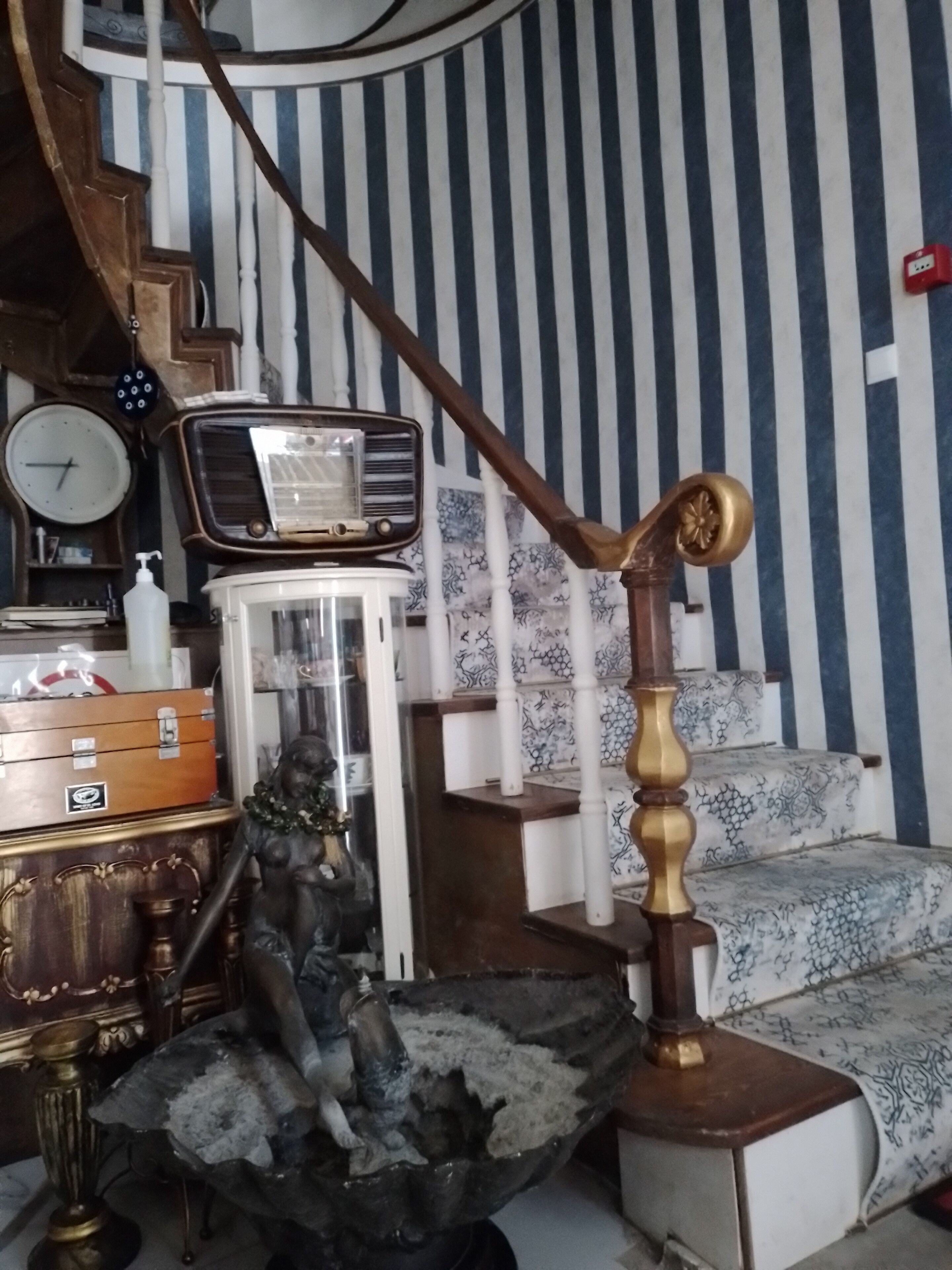 Una habitación con una escalera, una radio, un reloj y una estatua.