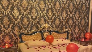 A bed with rose petals and red balloons, a nightstand with a candle, and ornate wallpaper. - Mazi Otel (Mudanya)