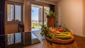 A modern hotel room with a large window, a dining table with a basket of fresh produce, and a chair. - 2 bedroom amazing apartment in Trappeto (Trappeto)