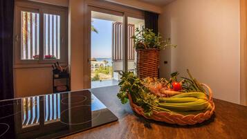 Une chambre d’hôtel moderne avec une grande fenêtre, une table à manger agrémentée d’un panier de produits frais et une chaise.