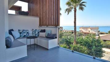 Un balcon doté d’un espace salon, d’une table et offrant une vue sur la mer.
