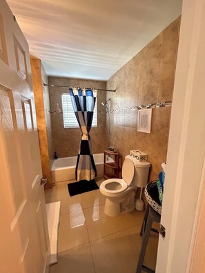 Un baño con bañera, inodoro y cortina de ducha.