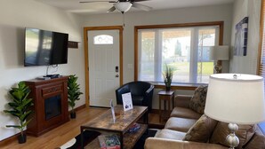 A living room with a television, a ceiling fan, a sofa, a coffee table, and a lamp.