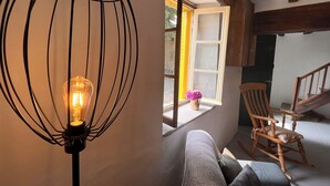 A cozy room with a wooden rocking chair, a patterned sofa, and a wall-mounted light fixture. - A tastefully renovated farmhouse in the tranquil la Creuse department of France. (Fursac)