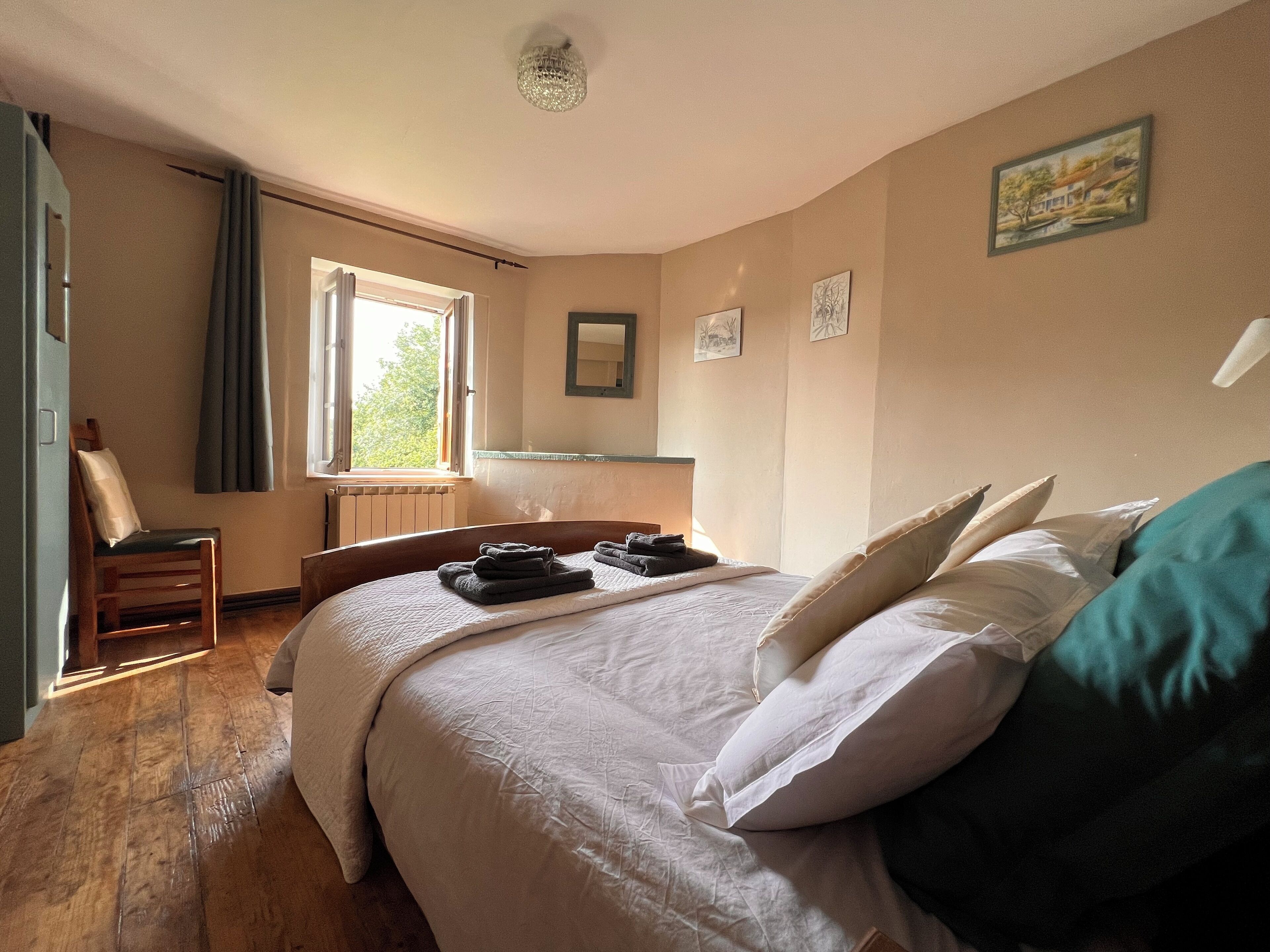 A bedroom with a bed, a chair, a window, and a radiator.