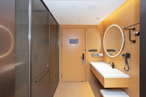 A modern bathroom with a glass shower enclosure, a wooden vanity with a mirror, and a towel rack.