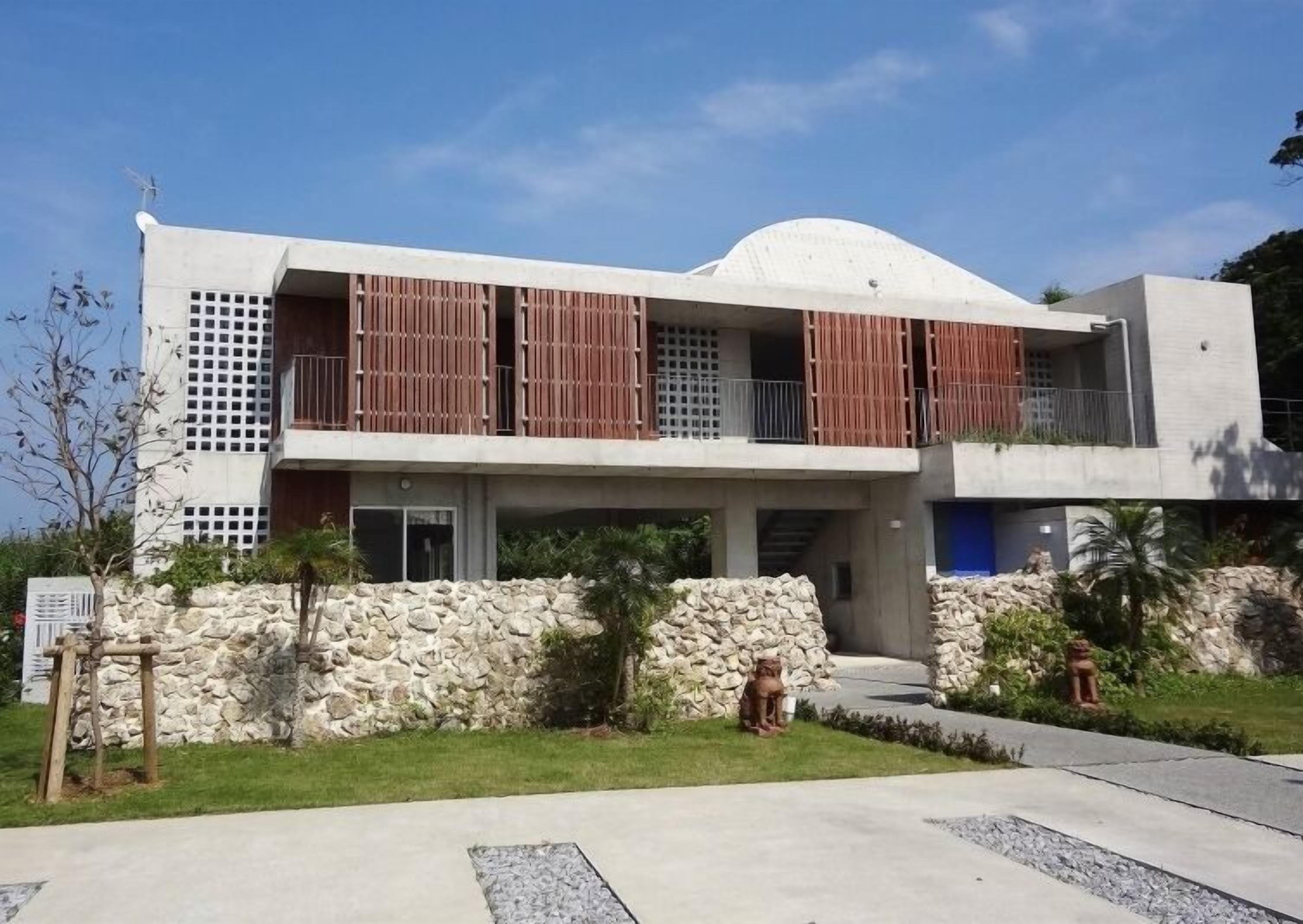 Un moderno edificio de dos pisos con techo plano, ventanas grandes y una pared de piedra en la fachada.