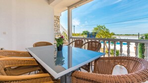 A balcony with wicker furniture, a glass table, and a view of a pool and greenery. - Beautiful home in Ceranje Gornje (Ceranje Gornje)
