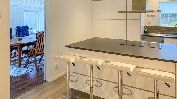 Een moderne keuken met een centraal eiland, roestvrijstalen apparatuur en een bar met krukken.
