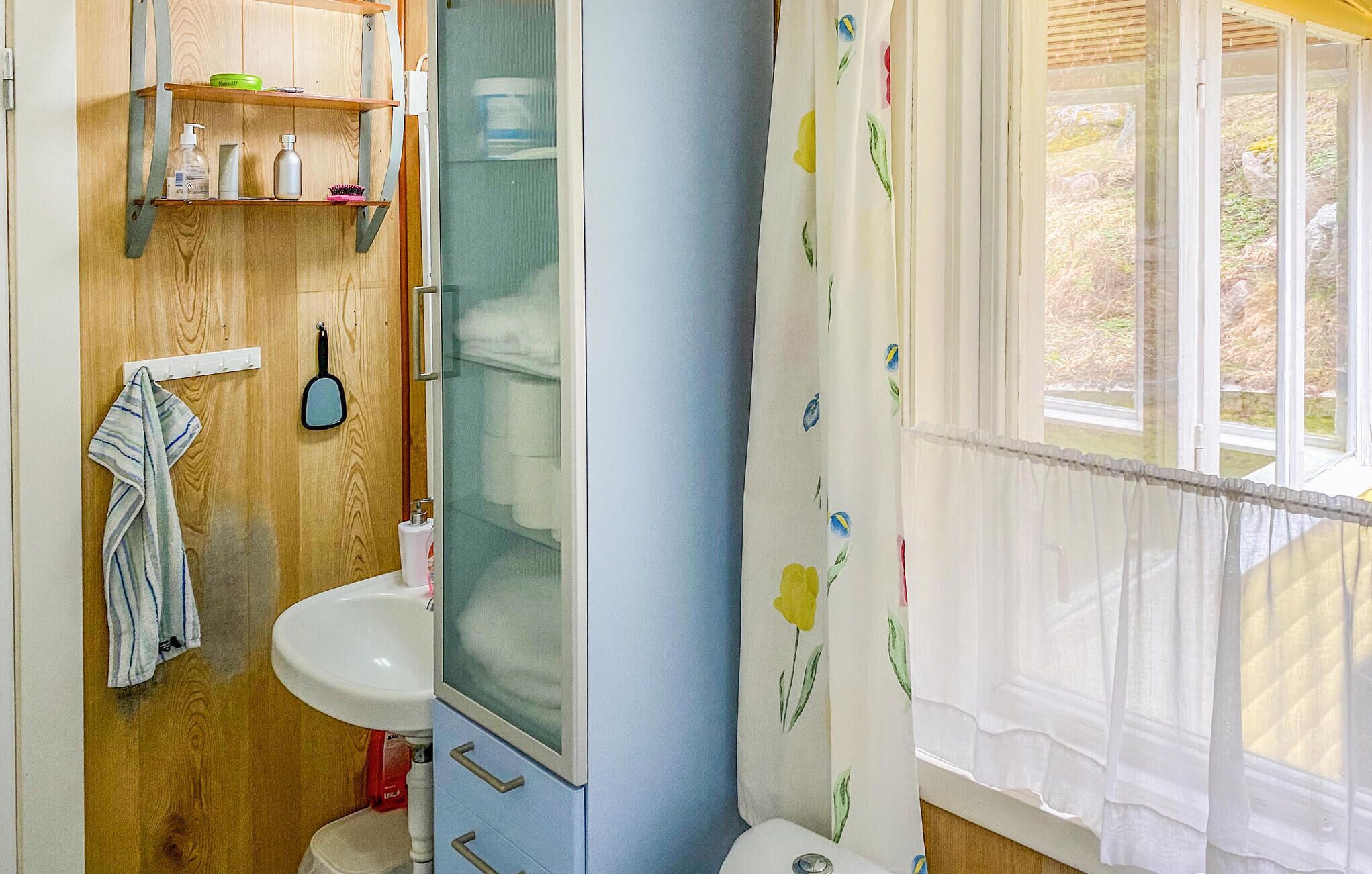 A bathroom with a wooden vanity, a sink, a mirror, and a shower curtain with floral patterns.