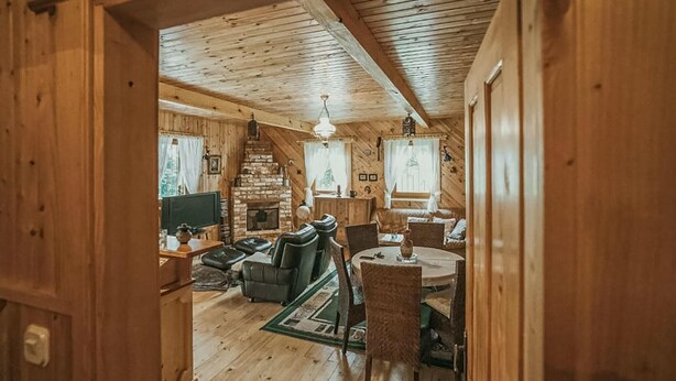 Un interior de cabaña acogedor con chimenea de piedra, paredes de madera y un comedor.