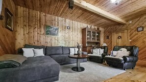 Una sala de estar acogedora con un sofá seccional, un sillón de cuero y una pequeña mesa redonda.