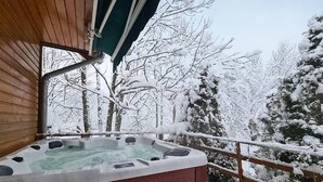 Una cabaña de madera con un jacuzzi en un balcón.