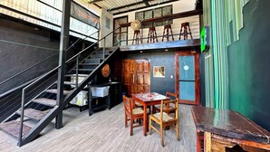 Een meerlaags interieur met een trap, een eetgedeelte met houten meubels en een groene wand met verticale strepen.
