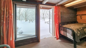 A cabin room with a bed, a window with curtains, and a view of a snowy forest. - Nice apartment in Vedum with WiFi (Vedum)
