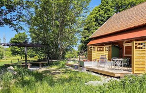 A wooden cabin with a tiled roof, a patio with outdoor furniture, and a pergola structure. - Nice apartment in Vedum with WiFi (Vedum)