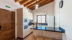 Una cocina con armarios de madera, encimera negra y ventana con vistas.