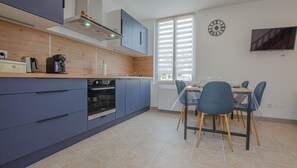 Eine moderne Küche mit blauen Schränken, einem eingebauten Backofen und einem Essbereich mit Tisch und Stühlen.