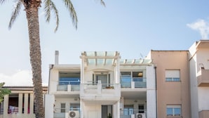 Un edifici de diverses plantes amb balcons, aires acondicionats i una palmera al primer pla.