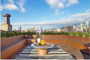 Une terrasse sur le toit dotée d’un foyer circulaire, d’espaces pour s’asseoir et offrant une vue sur la ville.