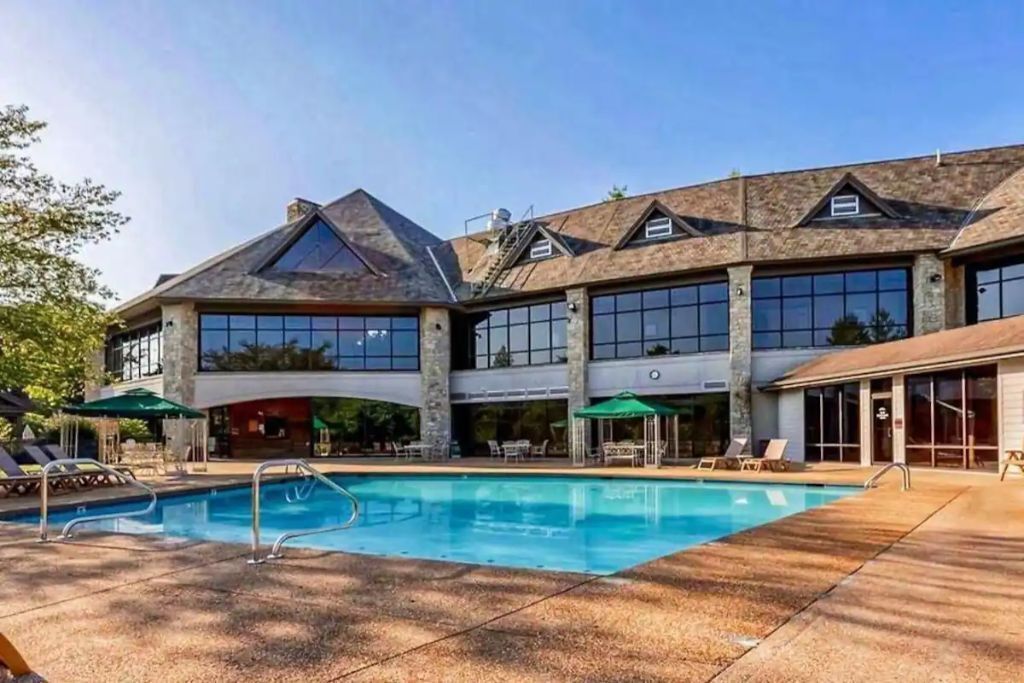 A large building with a swimming pool, outdoor seating, and a covered area.