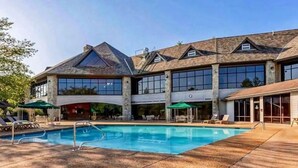 Un grand bâtiment doté d’une piscine, d’un espace extérieur aménagé et d’une zone couverte.