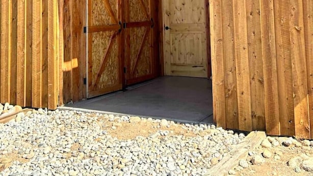 Una construcción de madera con techo inclinado, grandes puertas de madera y soportes metálicos.