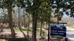 Een bord voor Fuquay Mineral Spring Park, met een natuurlandschap op de achtergrond.
