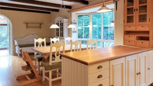 A kitchen with a wooden island, white cabinets, and a large window with a view of greenery.