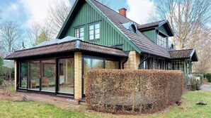A green house with a large glass front and a brick foundation.