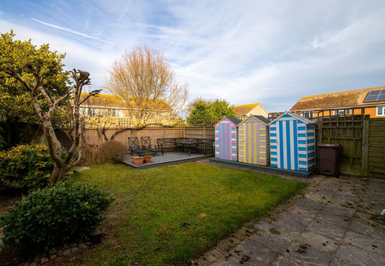 A backyard with a patio, a wooden fence, and colorful sheds.
