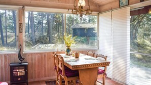 A wooden dining room with a table set for four, a chandelier, and a view of a forested area through large windows. - Stunning home in Borrby with WiFi (Borrby)