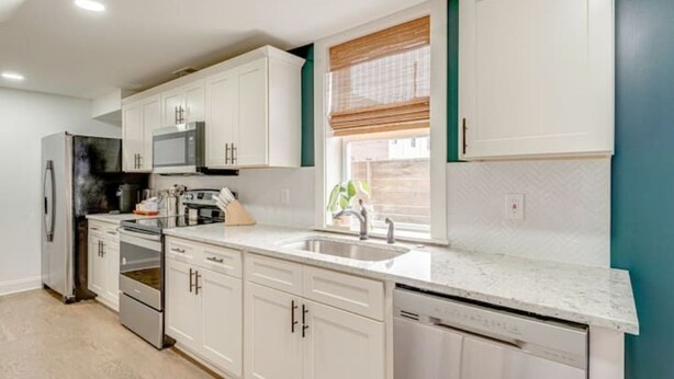 Una cocina moderna con armarios blancos, electrodomésticos de acero inoxidable y un ventanal con vistas.
