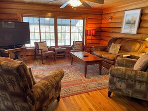Interior acogedor de una cabaña con piso de madera, televisor, sofá y una mesa de centro.
