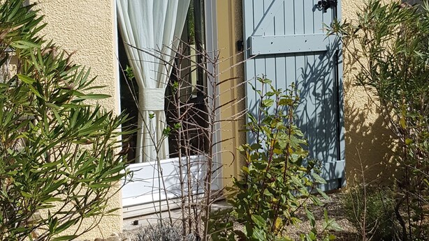 Un bâtiment à la façade beige, avec une porte bleue et un rideau blanc.