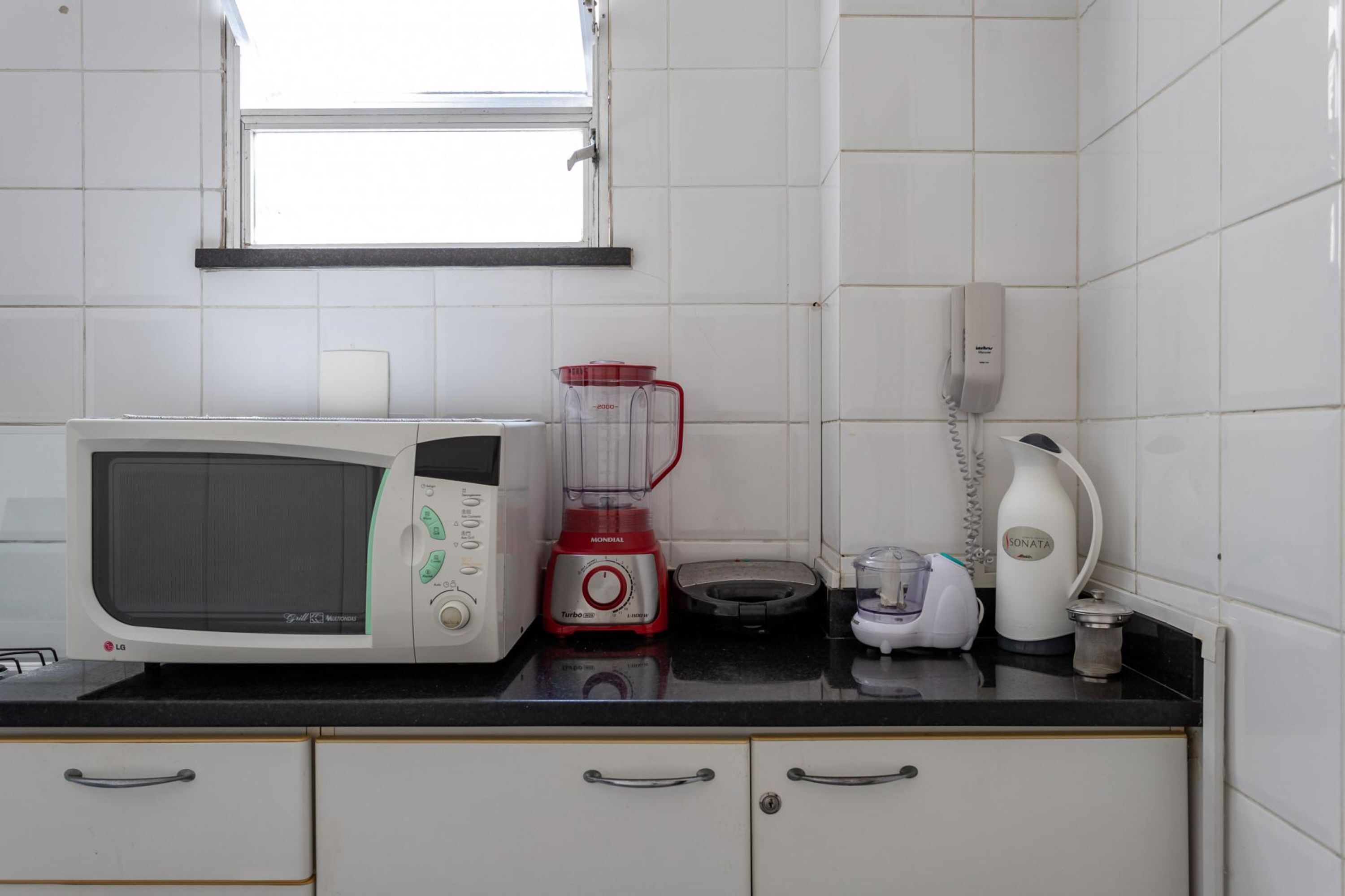 Eine Küche mit Mikrowelle, Mixer, Kaffeemaschine und Telefon auf der Arbeitsfläche.