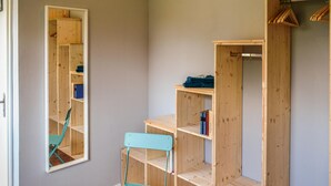 Ein Zimmer mit einem Holzschrank, einem Spiegel und einem türkisfarbenen Stuhl.