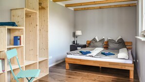 Ein Schlafzimmer mit einem hölzernen Bett, einem Nachttisch, einem Schreibtisch mit Stuhl und einer integrierten Bücherreol.