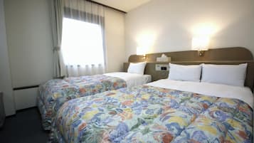 Une chambre d’hôtel avec deux lits, des couvre-lits à motifs floraux, une fenêtre avec des rideaux et des lampes fixées au mur.