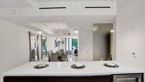 A modern kitchen with a white countertop, dark cabinets, and pendant lighting. - Fort Lauderdale Luxury Condo (Fort Lauderdale)