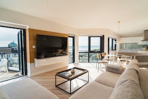 Relax in this stylish living room with a large flat-screen TV, comfortable sofa, and city views from the balcony.